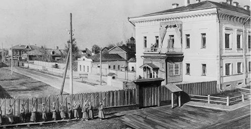 Őrségváltás a tobolszki kormányzói palotánál, amelynek első emeletén a Romanov-család lakott házi őrizetben. Az erkélyen Mária és Anasztázia nagyhercegnők állnak. A villanyoszloptól takarva látható az üvegház, amelynek tetején a cár és gyermekei szerettek napozni. A fényképet a fogság alatt a családot leggyakrabban fotózó Pierre Gilliard (1879–1962), a cári gyerekek francia nyelvtanára készítette, aki később Svájcba visszatérve könyvet is írt élményeiről; fotóarchívuma pedig ma a lausanne-i fotómúzeumban (Musée de l’Élysée) található.